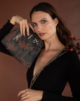 Woman holding a decorative clutch with a brown background